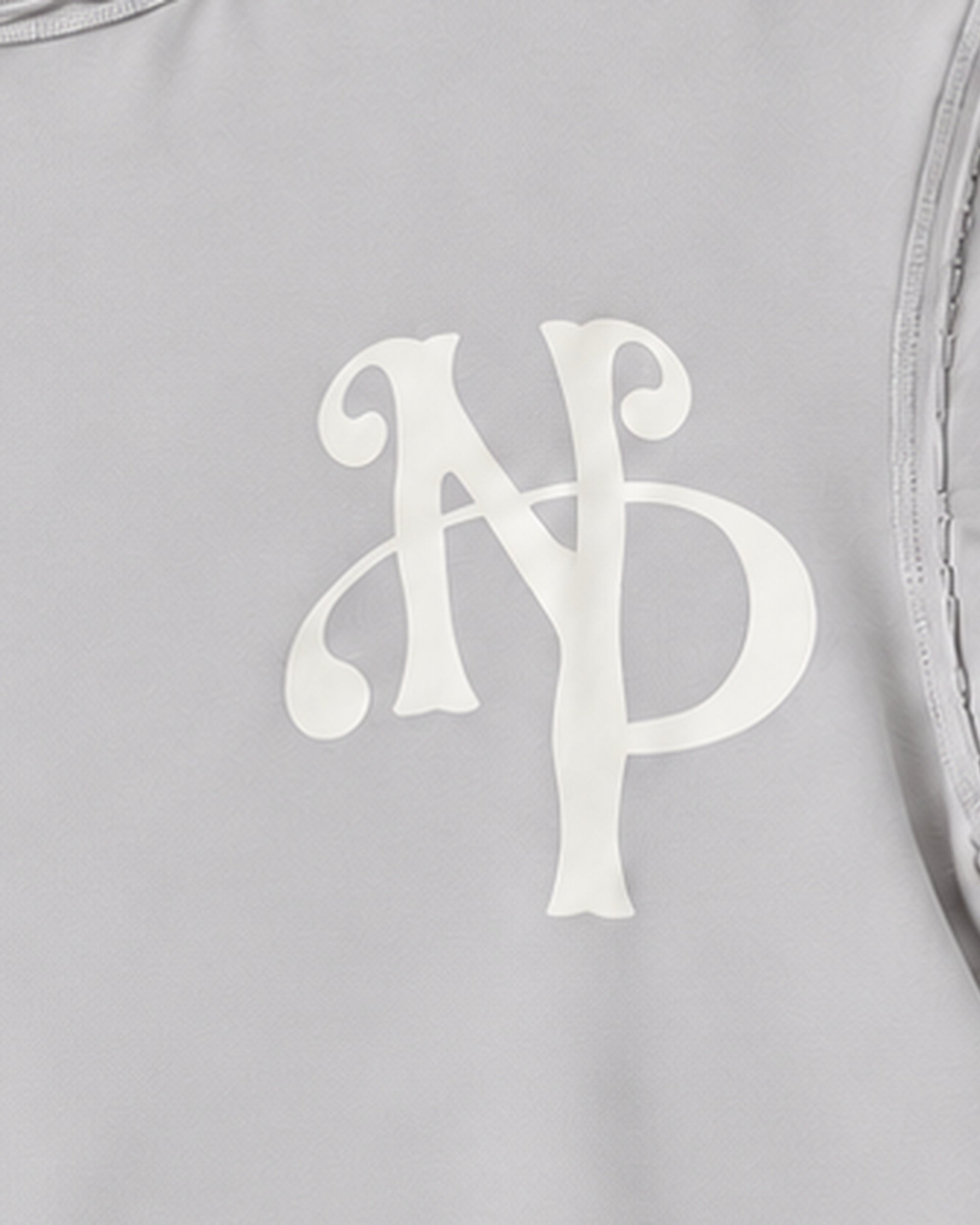 Detail crop of the cream NP chest monogram in the stone-grey T-shirt mockup.